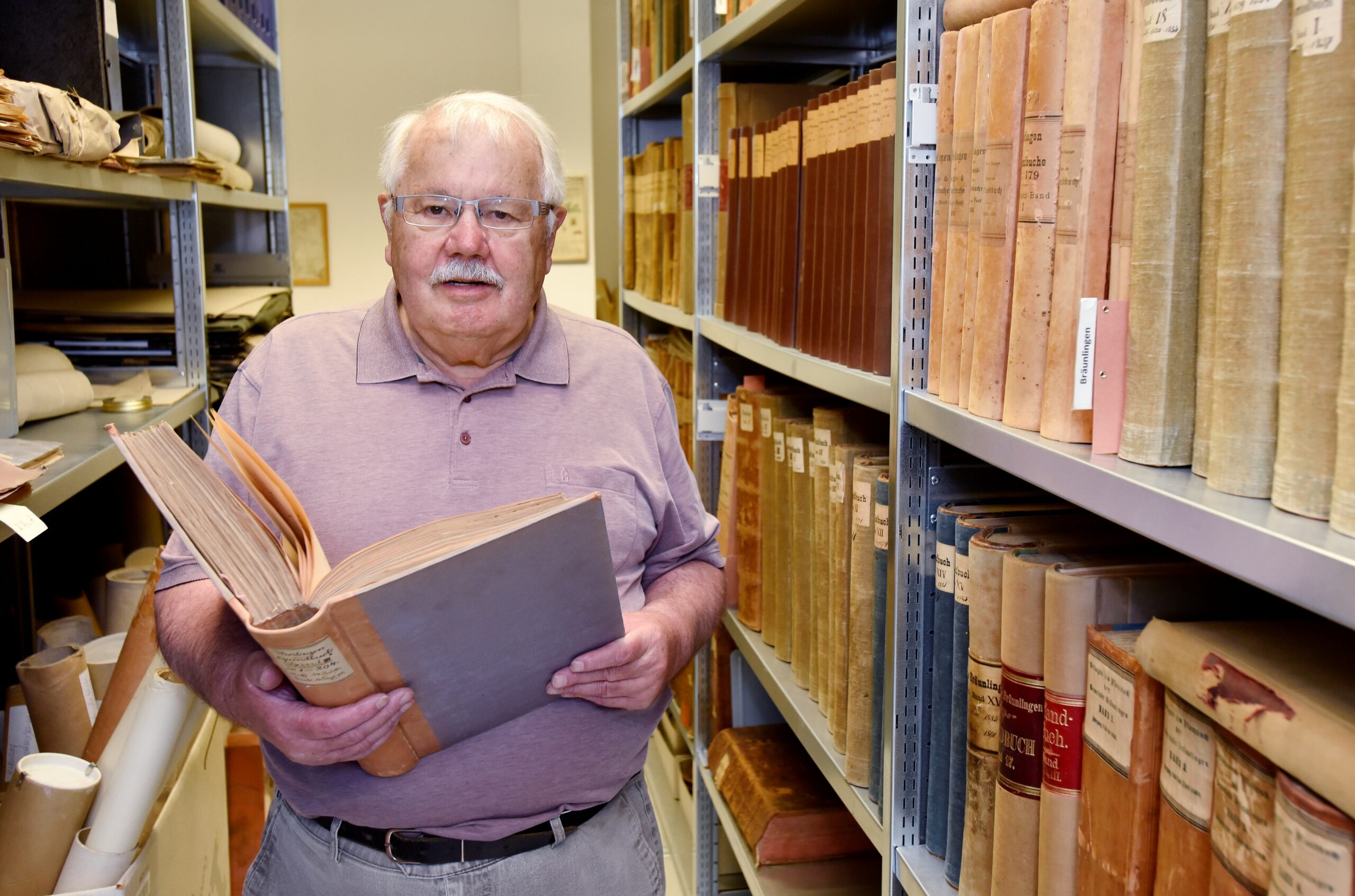 Foto Joachim Schweitzer im Stadtarchiv mit einem Buch in der Hand